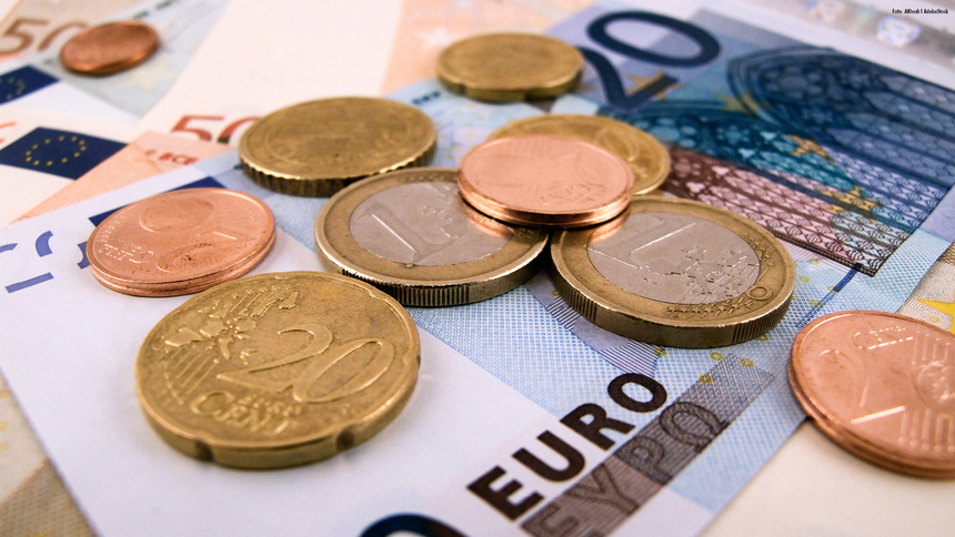 Euroscheine und Euromünzen frei auf einer Oberfläche verteilt 